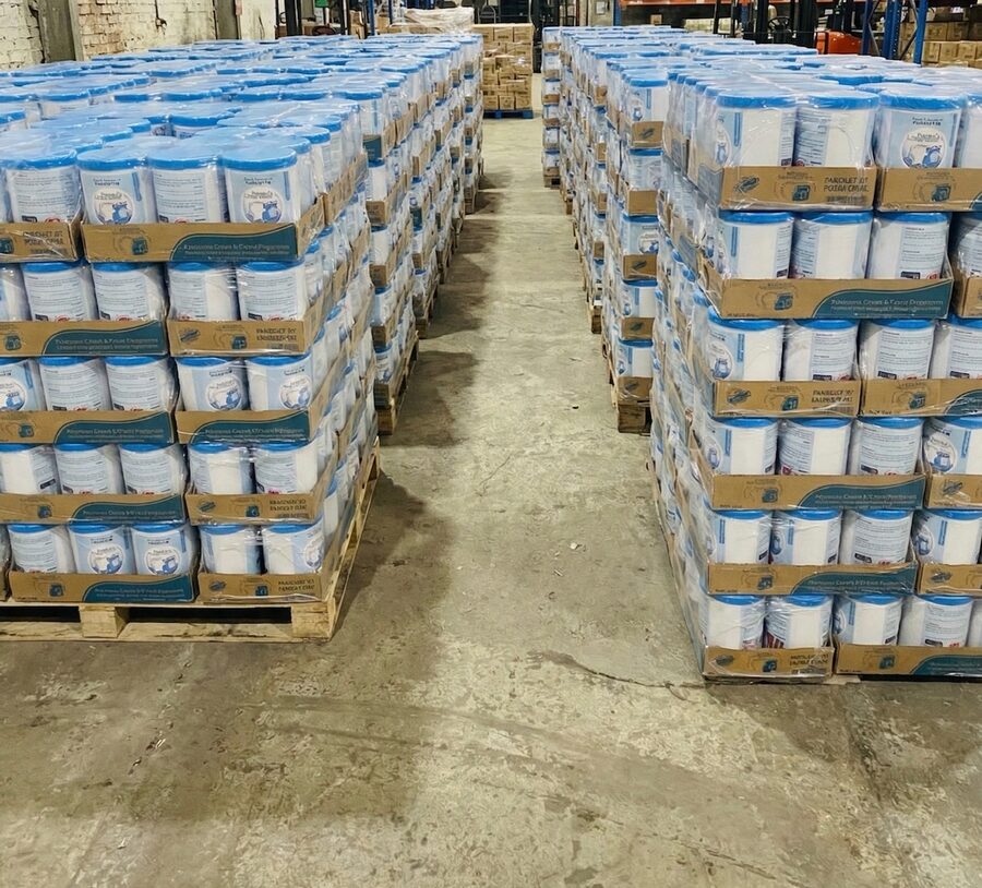 Pallets of shrink-wrapped Pakiza Laundry Cream tubs stacked in the ZSA Traders warehouse